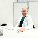 Médico sonriente en su escritorio, explicando para qué sirve un potenciador de testosterona.