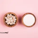 Dos cuencos de madera sobre fondo rosa: uno con cápsulas y otro con polvo blanco. Información sobre colágeno marino, efectos secundarios y beneficios.