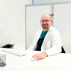 Médico sonriente en su escritorio, explicando para qué sirve un potenciador de testosterona.