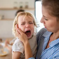 Madre consuela a su hija rubia, que llora desconsoladamente. Los terribles 3 años, una etapa difícil para todos.