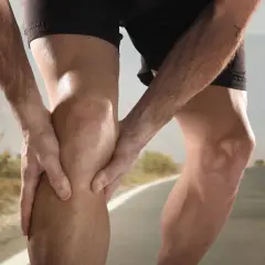Un corredor sujeta su rodilla, sintiendo dolor. El dolor de rodillas en adolescentes deportistas es común.