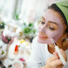 Mujer aplicándose mascarilla rosa, explorando los beneficios de los tipos de arcilla para la piel.