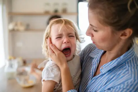 Madre consuela a su hija rubia, que llora desconsoladamente. Los terribles 3 años, una etapa difícil para todos.