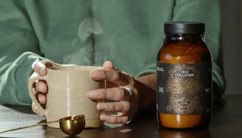 Manos sostienen taza humeante junto a un frasco de colágeno bovino, mostrando de qué está hecho el colágeno.