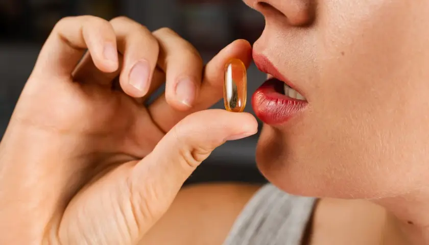 Mujer a punto de tomar una cápsula de colágeno. ¿Cuál es la mejor hora para tomar colágeno?