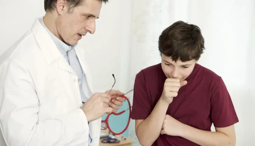 Médico examina a un niño tosiendo, buscando un remedio milagroso para la tos en niños.