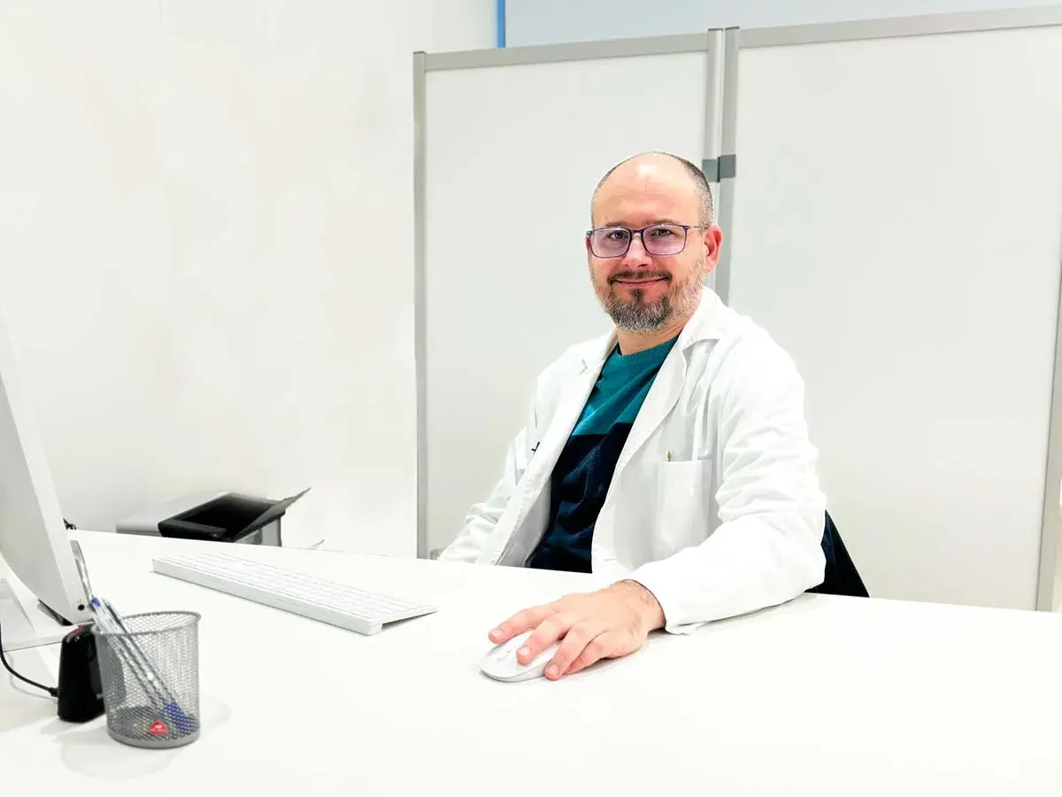 Médico sonriente en su escritorio, explicando para qué sirve un potenciador de testosterona.