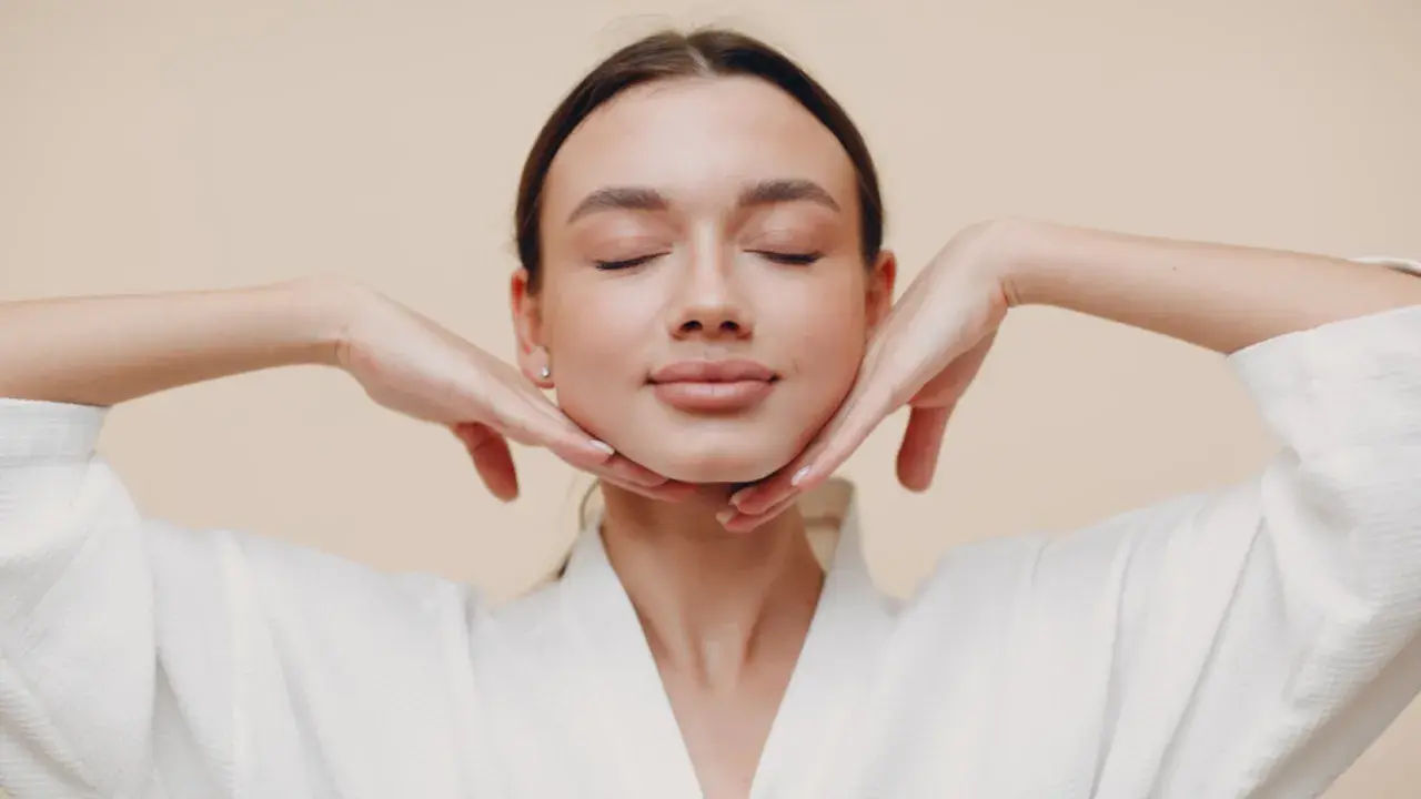 Mujer con ojos cerrados, manos en el mentón, disfrutando de los yoga facial beneficios.