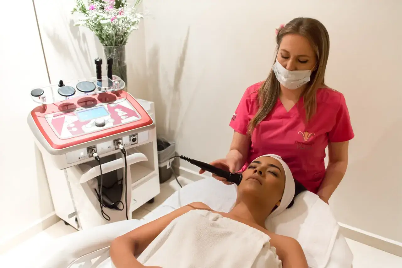 Esteticista aplica tratamiento para rejuvenecer el rostro de una clienta con equipo especializado.
