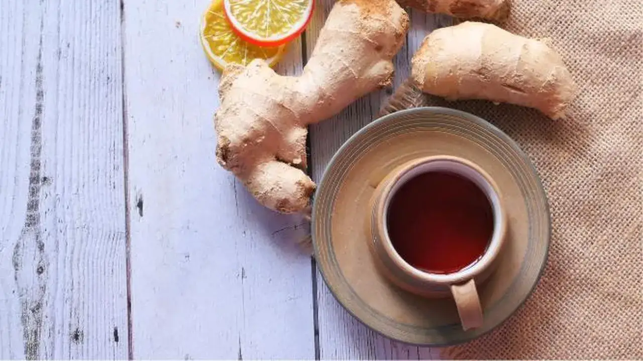 Té de jengibre antiinflamatorio muscular con rodajas de limón sobre una mesa de madera.