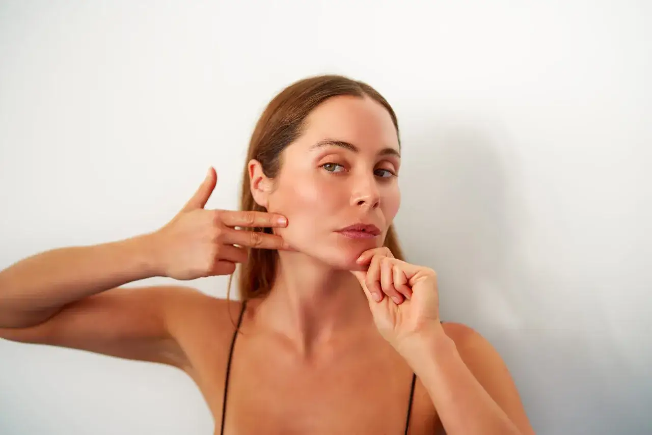 Mujer realizando ejercicios de yoga facial, mostrando cómo mejorar la firmeza y el contorno. Descubre los yoga facial beneficios.