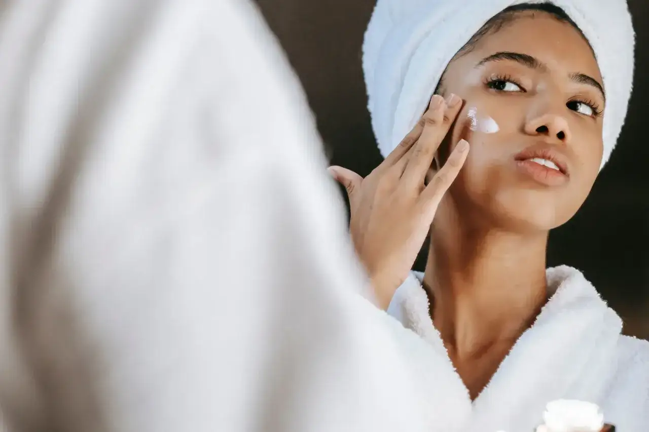 Mujer aplicándose crema en el rostro, un paso clave para mejorar la elasticidad de la piel y lucir radiante.