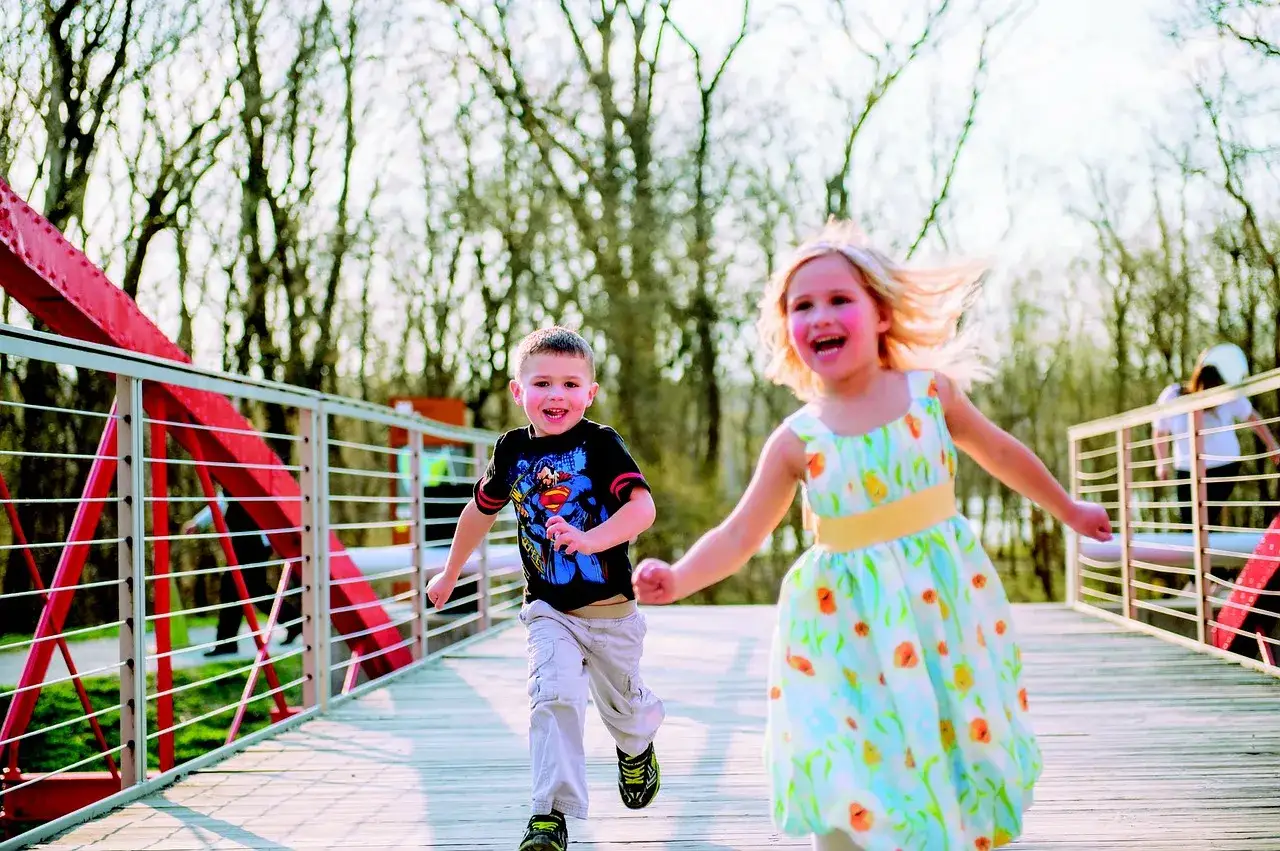 Mi hijo de 2 años corre feliz con su hermana por un puente.